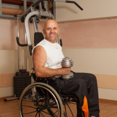 man in wheelchair pumping iron in the gym with a dumbbell